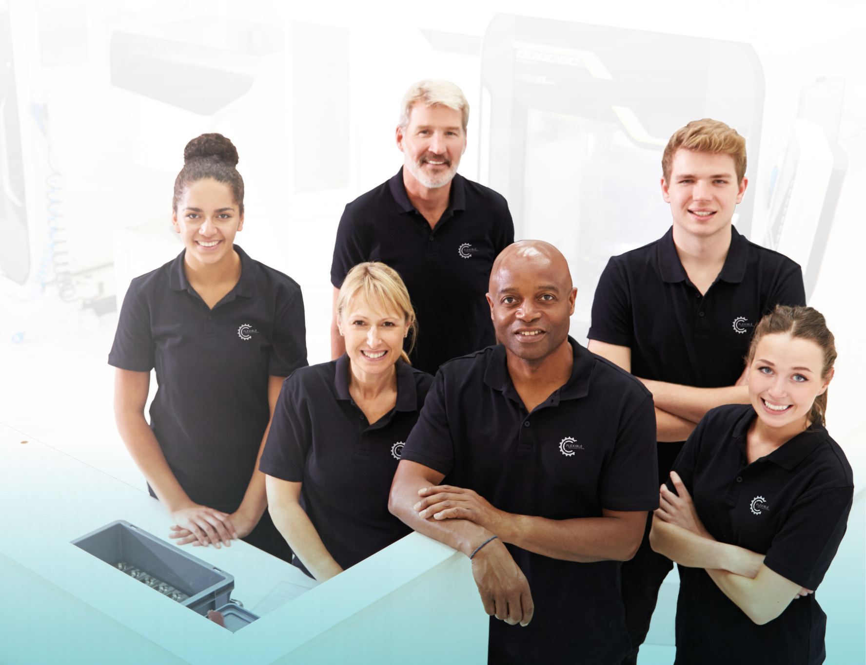 Six members of the FMS team in branded black polo shirts, smiling in the factory